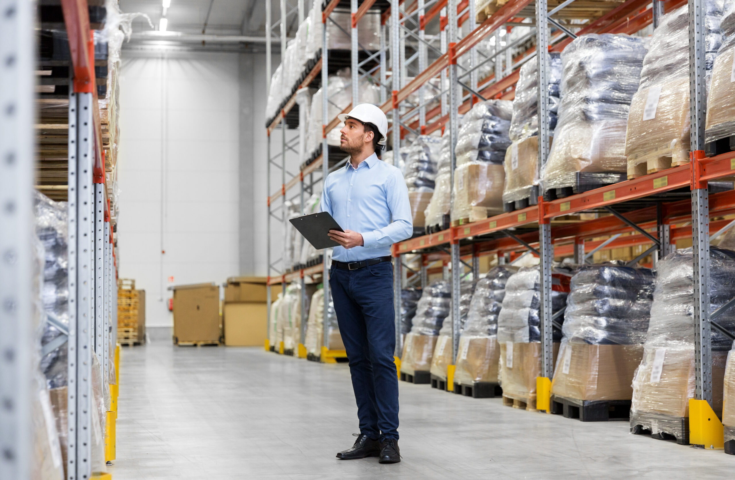 businessman in helmet with clipboard at warehouse